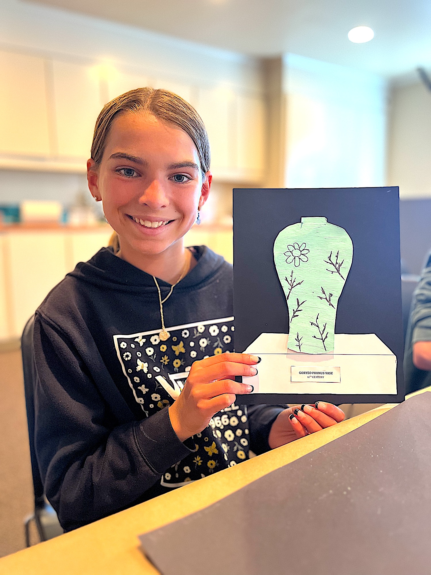 A child holding a completed activity, a celadon vase demonstrating a Korean pottery inlay technique - a creative art activity for teaching A SINGLE SHARD by Linda Sue Park, from LitWits Workshops
